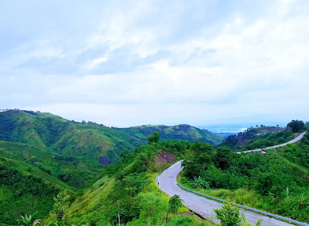 A road winding through green hills at Palavilla, Lutayan