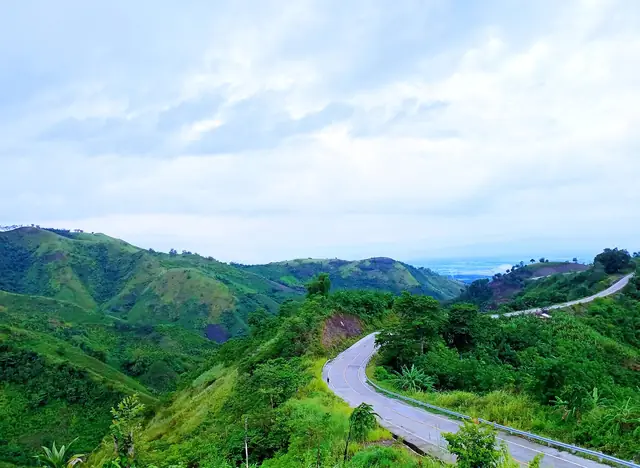 A road winding through green hills at Palavilla, Lutayan