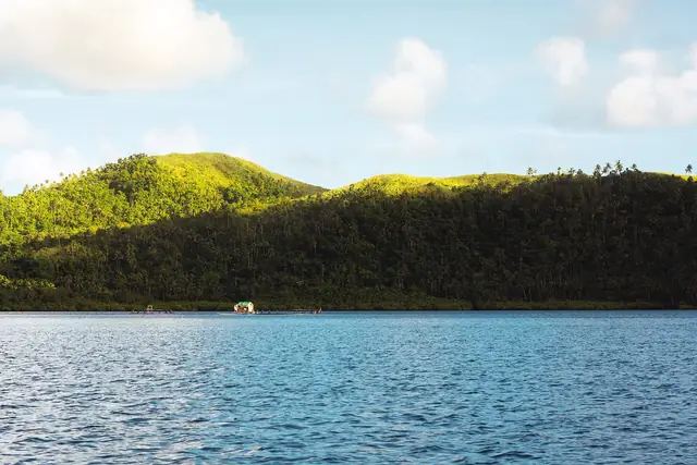 Green hills of Middle Bucas Grande across calm water, seen from Dapa